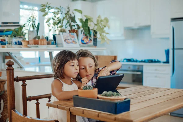 Pequeño niño y su hermana utilizan tableta digital juntos en la sala de estar —  Fotos de Stock