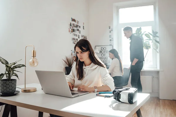 Pessoa feminina séria trabalha no laptop na área de trabalho no escritório — Fotografia de Stock