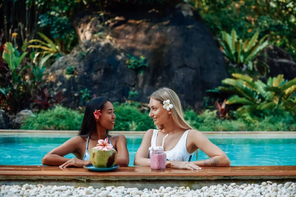 Deux jeunes femmes posent à la caméra se regardant dans la piscine — Photo