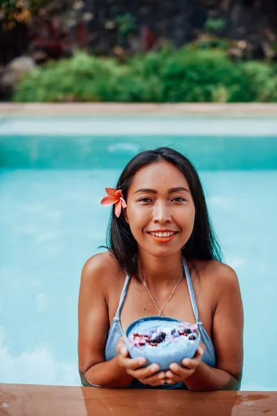 Femme souriante en bikini avec peau bronzée et nourriture aux fruits dans la piscine — Photo