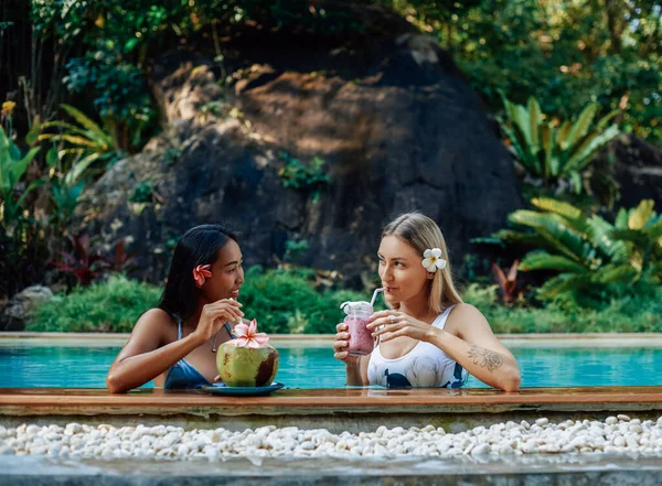 Deux filles en bikini boivent des cocktails et nagent dans la piscine dans un hôtel de luxe — Photo