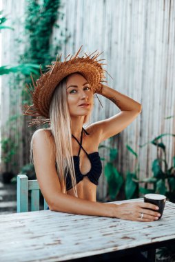 Hasır şapkalı kadın gezgin masada oturuyor ve kameraya bakıyor.