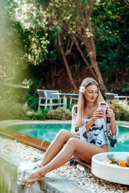 Yüzme havuzunda egzotik kokteylleri olan genç bir kadın.