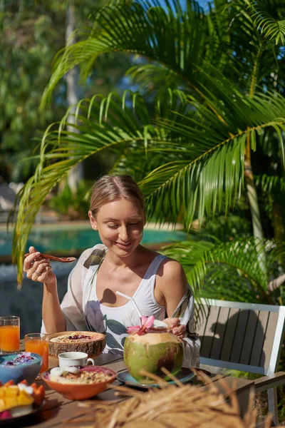 Glädjande kvinna äter hälsosam mat på sin semester i Thailand nära poolen — Stockfoto
