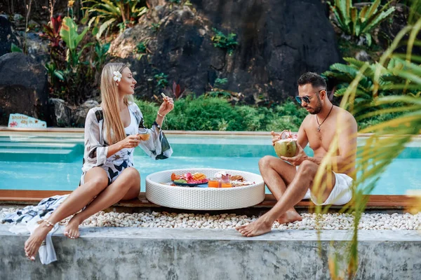 Gifta turister äter och dricker asiatisk mat i bakgrunden av poolen — Stockfoto