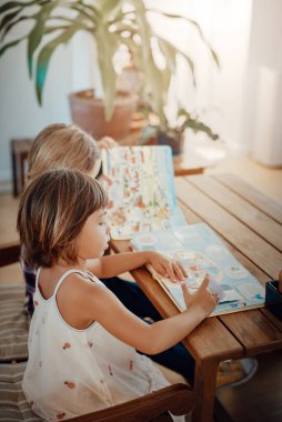 Masada kitaplarla birlikte beyaz erkek ve kız kardeşler dairede.