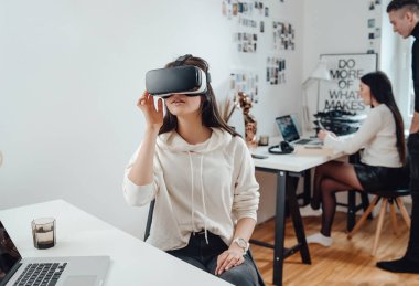 Kadın iş adamı ofiste sanal gerçeklik kulaklığı takıyor