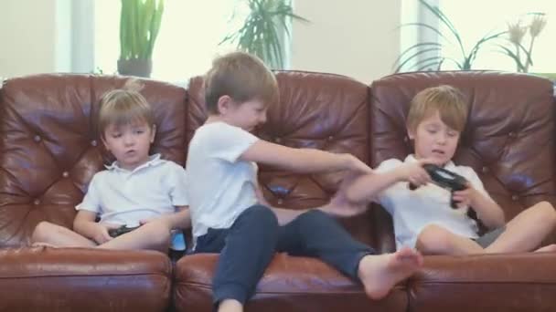 Drei Jungen spielen zu Hause Videospiele und sitzen auf dem Sofa — Stockvideo