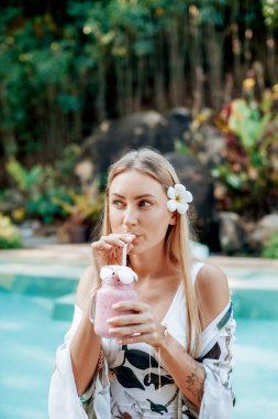 Güzel bir kadın yüzme havuzunda kokteyl içer.