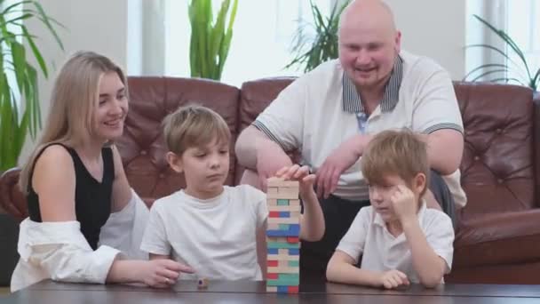 Familia despreocupada de dos hijos jugando en juego de mesa, torre de madera en la sala de estar — Vídeo de stock