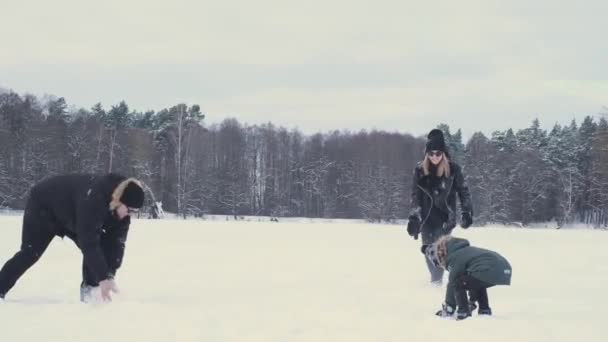 快乐的家庭，一个孩子冬天在河边的森林里打雪球 — 图库视频影像