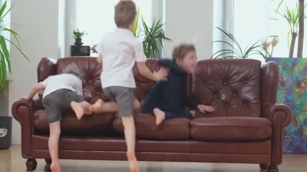 Drie vrolijke broers en gelukkige ouders springen op de bank — Stockvideo