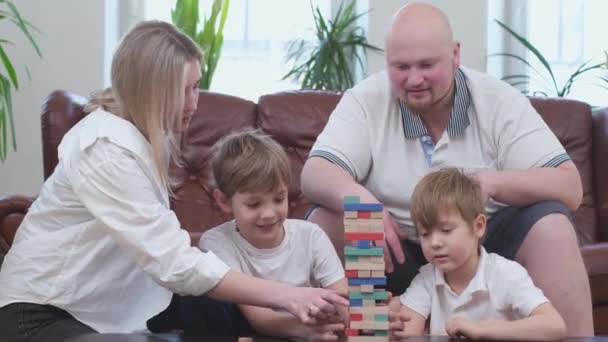 Familia despreocupada de dos hijos jugando en juego de mesa, torre de madera en la sala de estar — Vídeo de stock