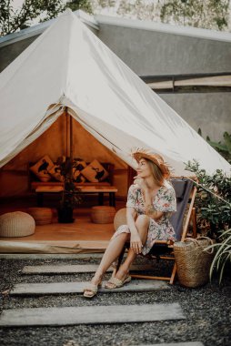 Hasır şapkalı mutlu kadın kampta sandalyede oturuyor.