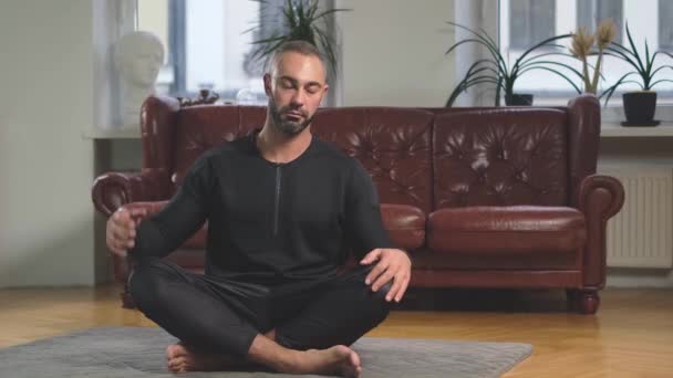 Сильный человек практикующий йогу делает изгибы в сторону расслабляясь в позе лотоса — стоковое видео