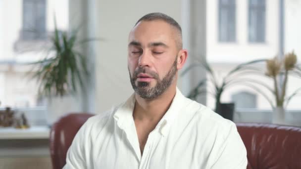 Hombre con los ojos cerrados respirando profundamente después del trabajo duro, vistiendo camisa blanca — Vídeos de Stock