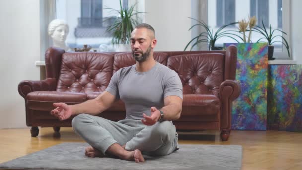 Fešák sportovní muž zprostředkování, otevřené a zavřené oko v moderním obývacím pokoji on-line — Stock video