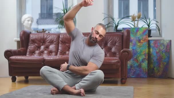Deportista haciendo curvas a un lado relajándose en posición de loto en la sala de estar — Vídeos de Stock