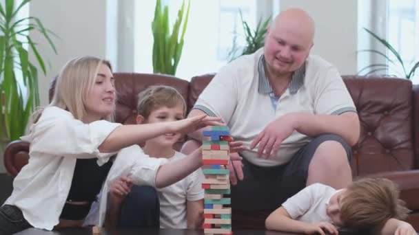 Familia de cuatro personas jugando en juego de mesa, torre de madera — Vídeo de stock