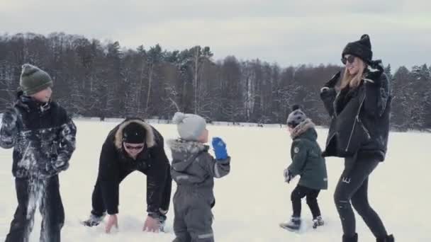 Lycklig familj med trädbarn leker snöbollar på vintern i skogen på floden — Stockvideo