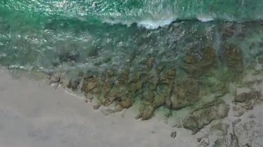 Gök mavisi okyanus dalgalarının çarptığı sahilin yukarıdan aşağıya bakan görüntüsü.