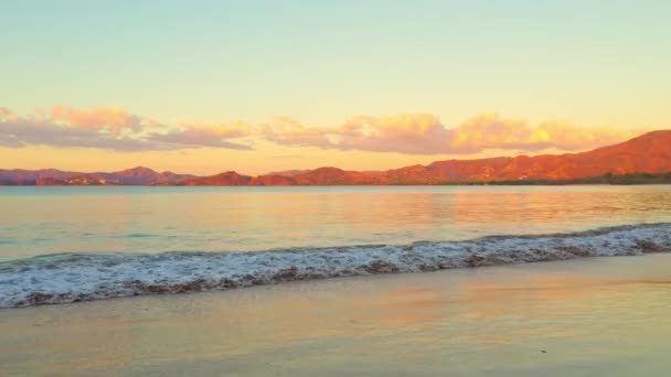 海浪拍打着沙滩，高山长距离，美丽的金色天空 — 图库视频影像