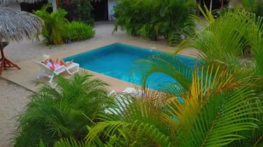 Kosta Rika 'daki tropik iklimlerde havuzda uzanan genç kadınları rahatlatmak, İHA atışı.