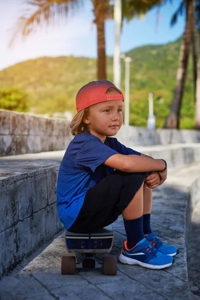 独身少年は外を見てスケートボードに座っている — ストック写真