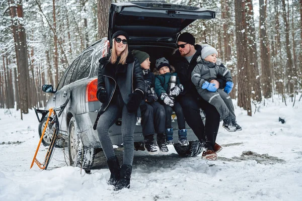 Foresta innevata e famiglia caucasica in posa sul bagagliaio dell'auto durante il giorno — Foto Stock