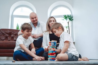 Kafkasyalı ebeveynler çocuklarıyla bir masa oyunu oynuyorlar.