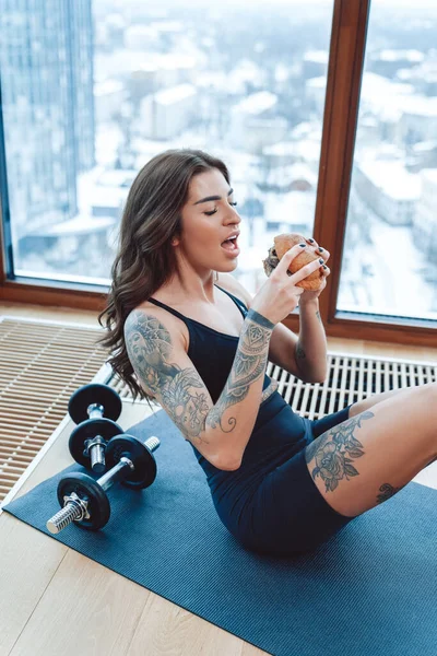 Pretty and sexy woman eating tasty hamburger on skyscrapers background. — Foto Stock