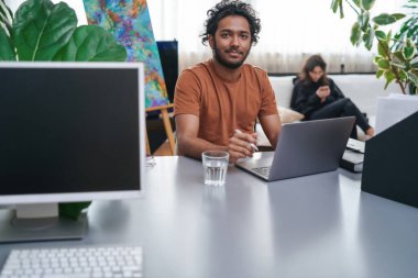 Modern ofis ve Hintli işçi kanepede dizüstü bilgisayar ve kadın kullanıyor.