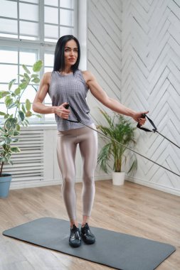 Siyah saçlı güçlü kadın trenler ve direniş bantları çekiyor.