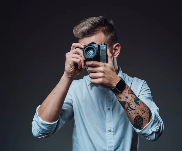 Tattooed hipster with doing shot with his digital camera