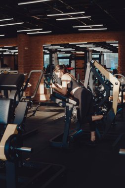 Genç sporcu, modern spor salonunda bir eğitim makinesiyle egzersiz yapıyor.