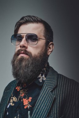 Şık giyinen, güneş gözlüklü şık bir adam.