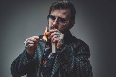 Gri arka planda Küba purosu olan şık ve sakallı hippi.