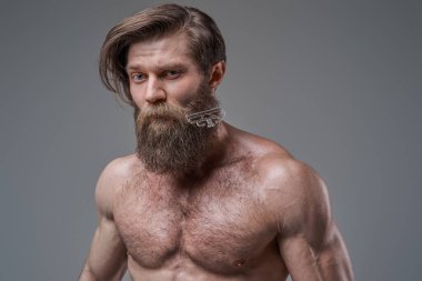 Taraklı şık vücut geliştirici gri arka planda poz verir