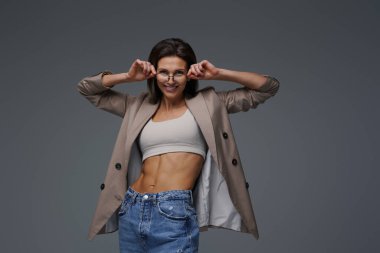 Sportif ve anlamlı kadın gözlüklerini tutarak poz veriyor.