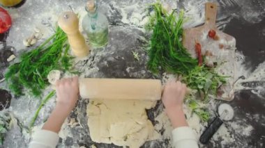Etrafı dağınıklık ve yemek pişirme konseptiyle çevrili pizza hazırlayan bir çocuğun yakın plan görüntüsü..