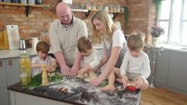 Šťastný mladý rodina maminka táta a ty děti vaření spolu, kuchyně interiér. — Stock video