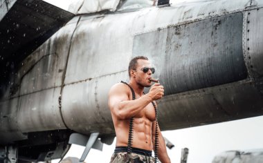 Havaalanında puro tüttüren kaslı ve yakışıklı asker.