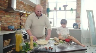 Üç kişilik beyaz bir aile tuğla mutfak arka planında pizza yapıyor..
