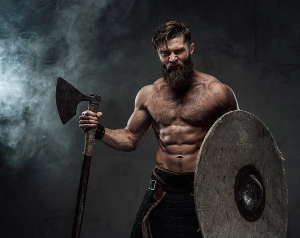 Woedende viking met schild en bijl in donkere achtergrond — Stockfoto