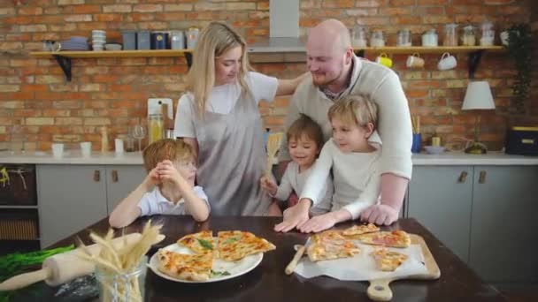 Atrakcyjni biali rodzice patrzący na dzieci, trzech chłopców bawiących się w kuchni. — Wideo stockowe