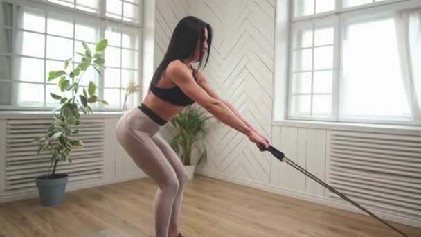 Fitness σέξι κορίτσι στέκεται κάνει ασκήσεις με expander αντλίες τα χέρια της, πατήστε. — Αρχείο Βίντεο