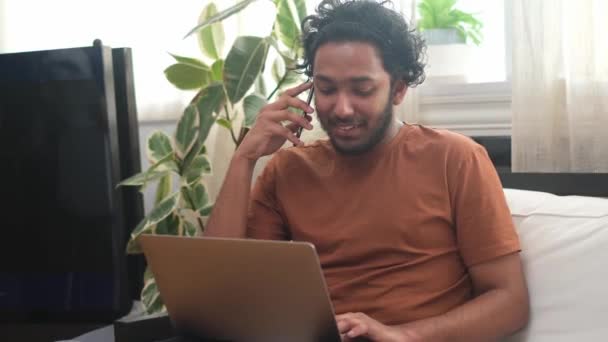 Jeune homme d'affaires indien souriant parlant au téléphone au bureau avec des plantes. — Video