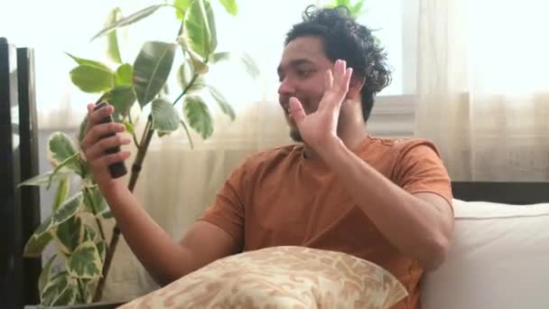 Junger Hindu-Mann spricht per Videoanruf, während er auf der Couch im Wohnzimmer sitzt. — Stockvideo