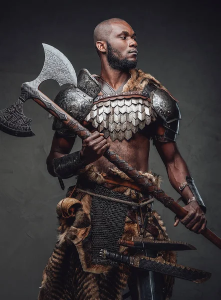 Wild african soldier wielding an axe and posing in dark background