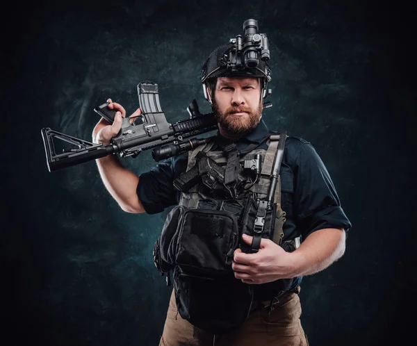 L'uomo combattivo posa in uno sfondo scuro con fucile guardando la fotocamera — Foto Stock